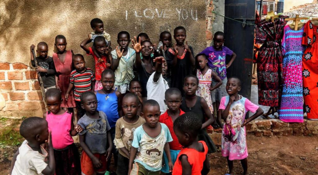 group of children in Uganda. I Love you is written on the wall in chalk