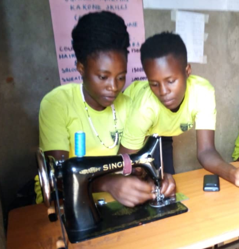 IMG_3885 Two teenaged girls use a black sewing machine in Uganda